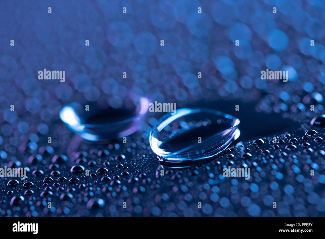selective focus of contact lenses and water drops on blue background Stock Photo