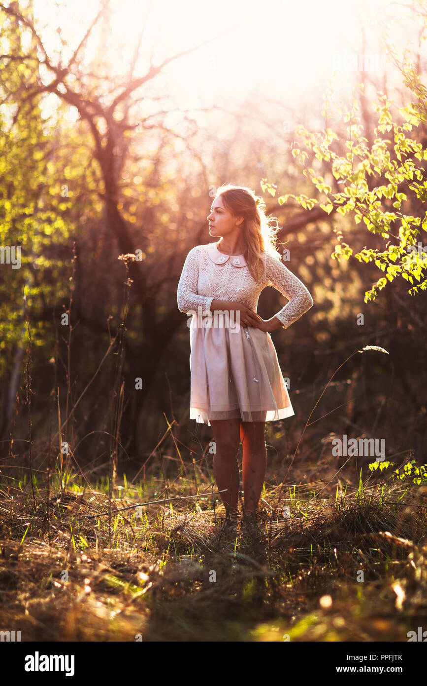 Beautiful girl standing in a field on a sunset background Stock Photo ...
