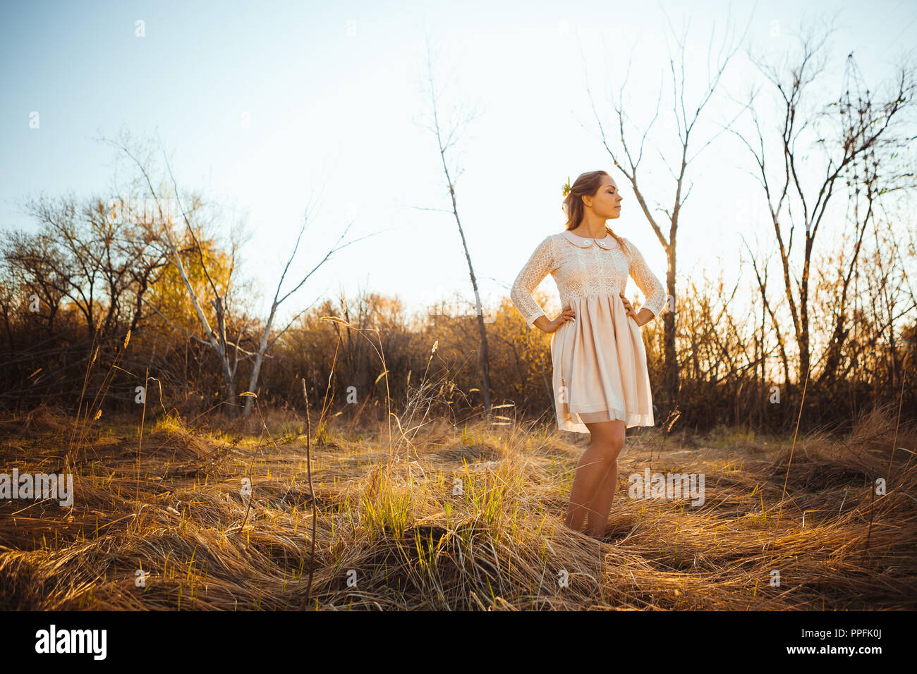Beautiful girl standing in a field on a sunset background Stock Photo ...