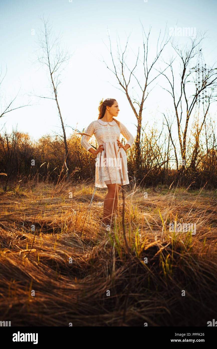 Beautiful girl standing in a field on a sunset background Stock Photo ...
