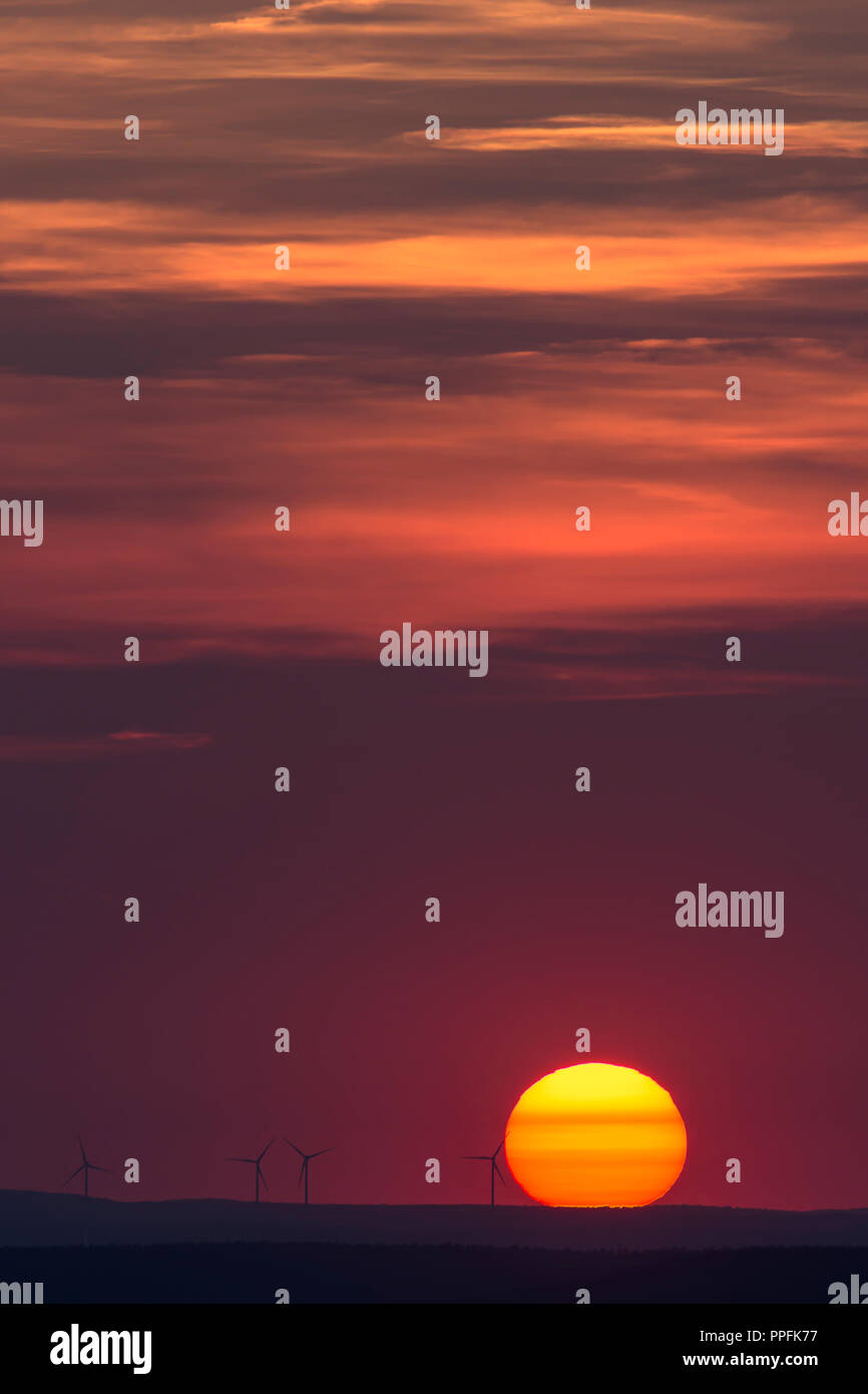 Glowing sun and silhouettes of wind turbines on the horizon, sunset, Bavaria, Germany Stock Photo