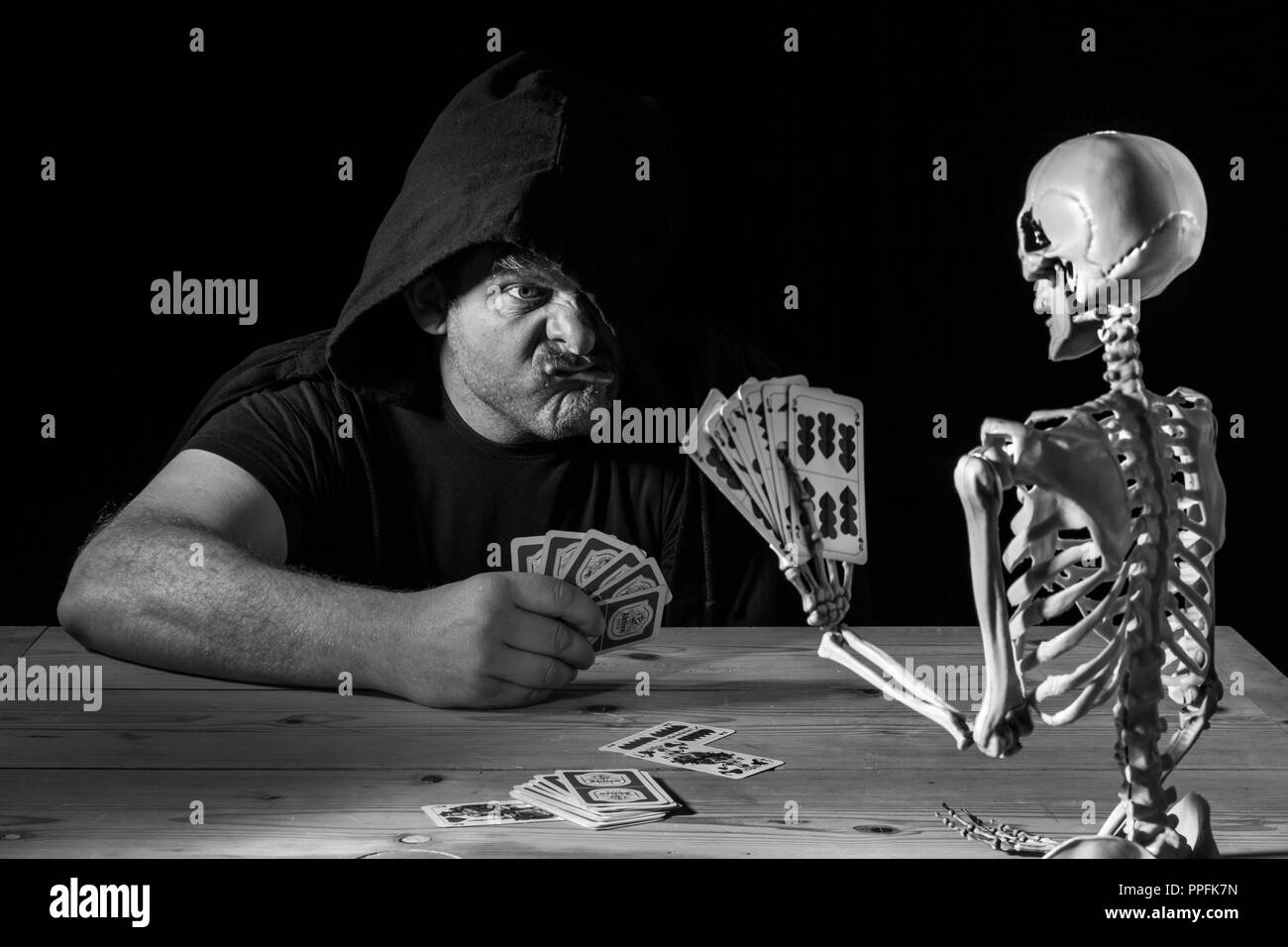 Man plays cards with a skeleton, his last game, symbol image for life and death, Germany Stock Photo