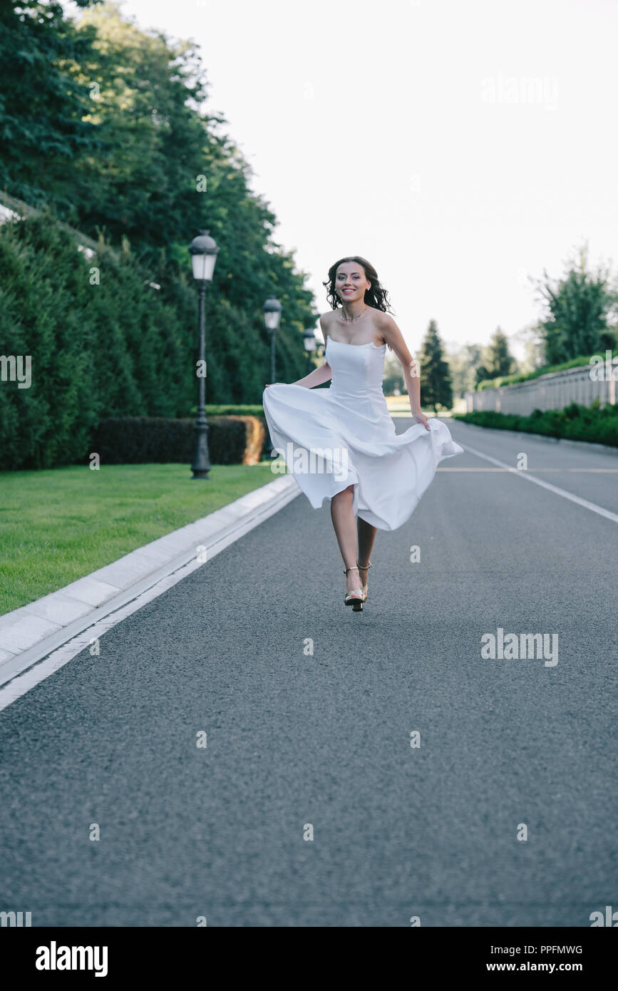 beautiful happy bride in wedding dress running on road Stock Photo Alamy