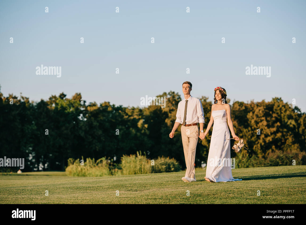 beautiful happy young wedding couple holding hands and walking together ...
