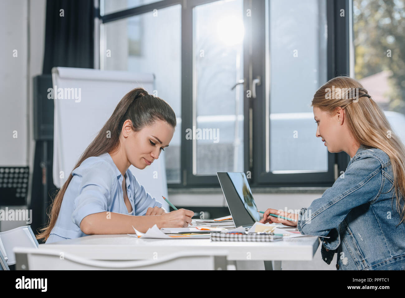 side view of two businesswomen working in office Stock Photo - Alamy