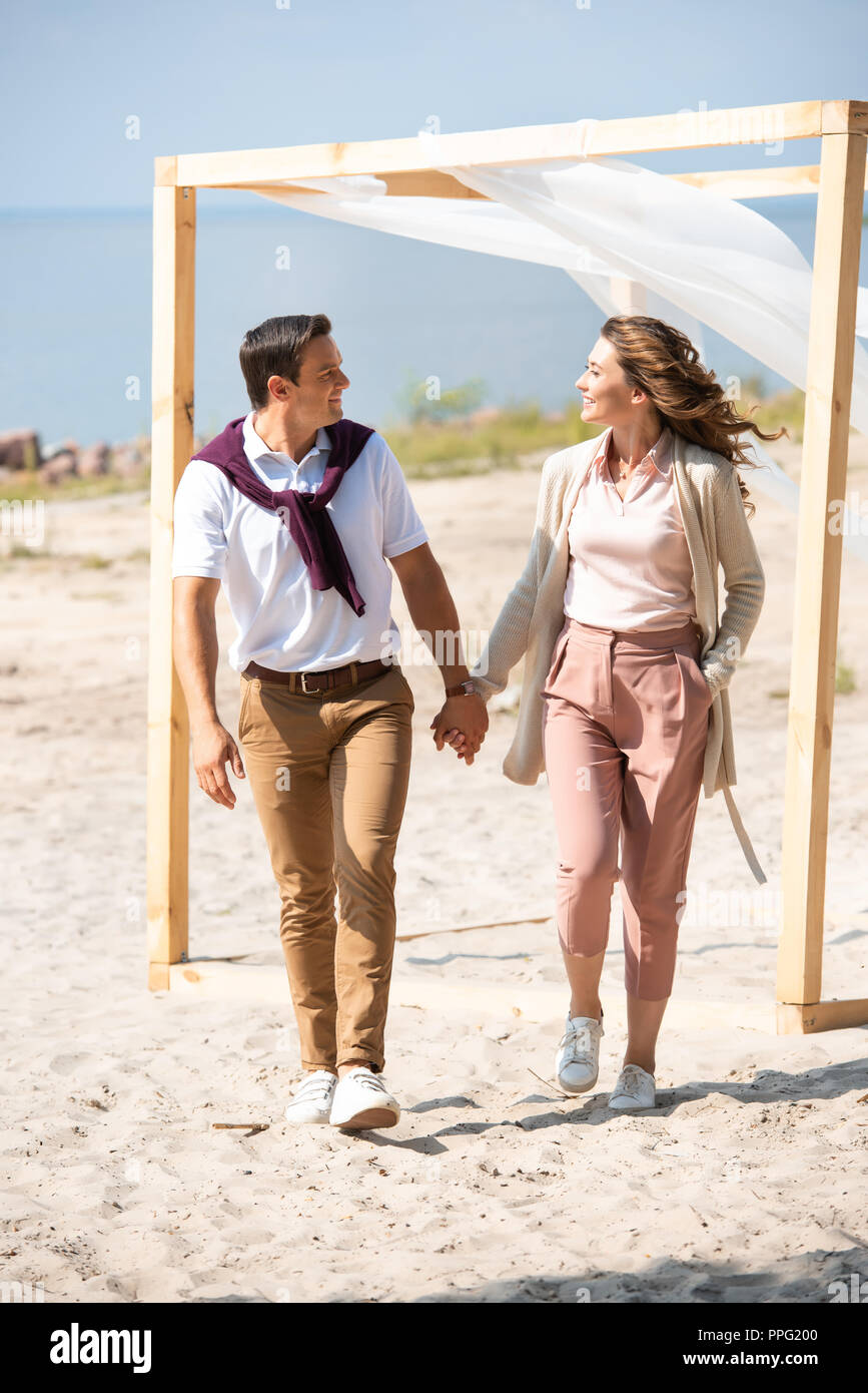 happy couple holding hands while walking on sandy beach Stock Photo - Alamy