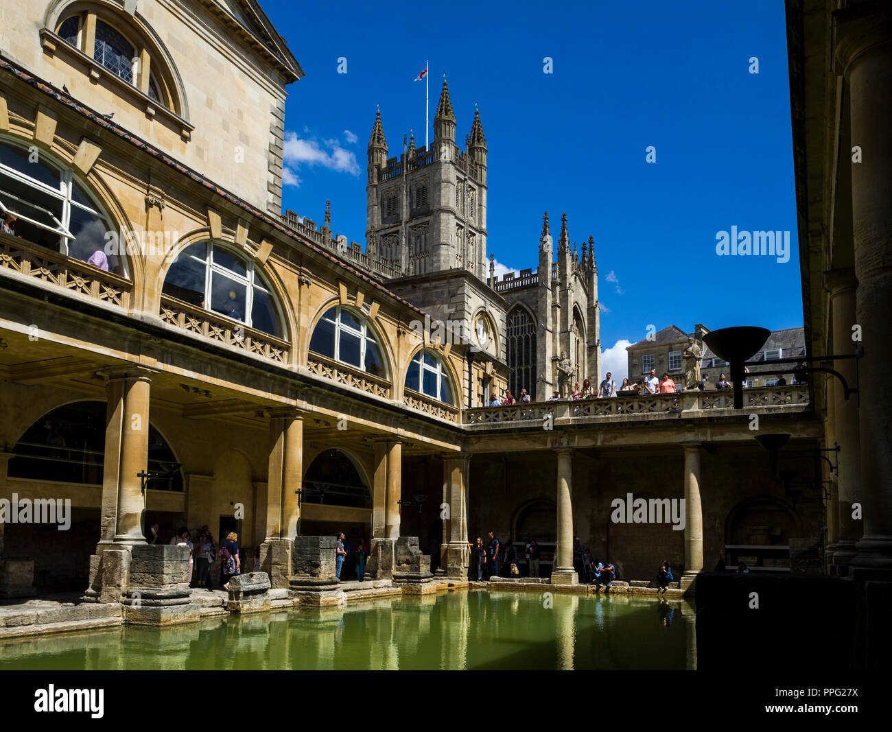 Visitors exploring the historic Roman Baths with Bath Abbey towering
