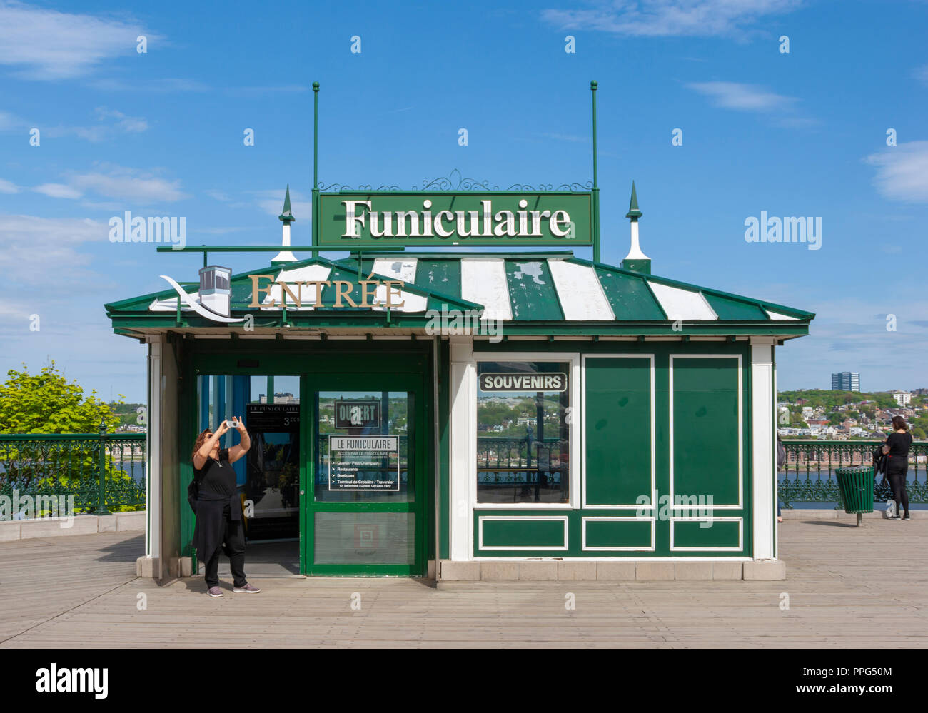 The upper level station of the Old Quebec Funicular, on the Dufferin Terrace. A woman takes a snapshot of the nearby Château Frontenac hotel. Stock Photo