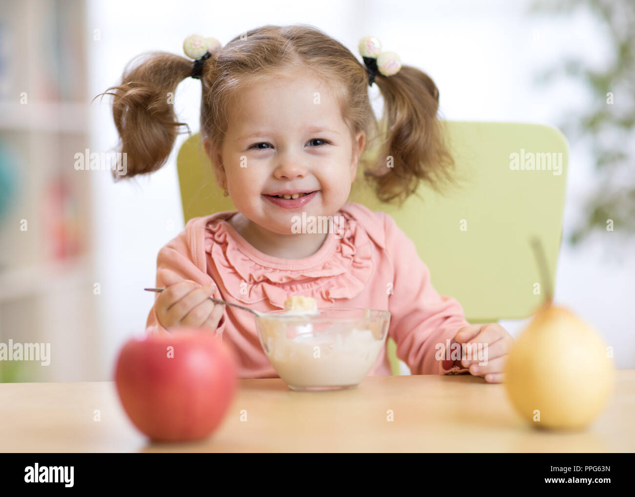 baby girl eating yogurt and fruits at home Stock Photo Alamy