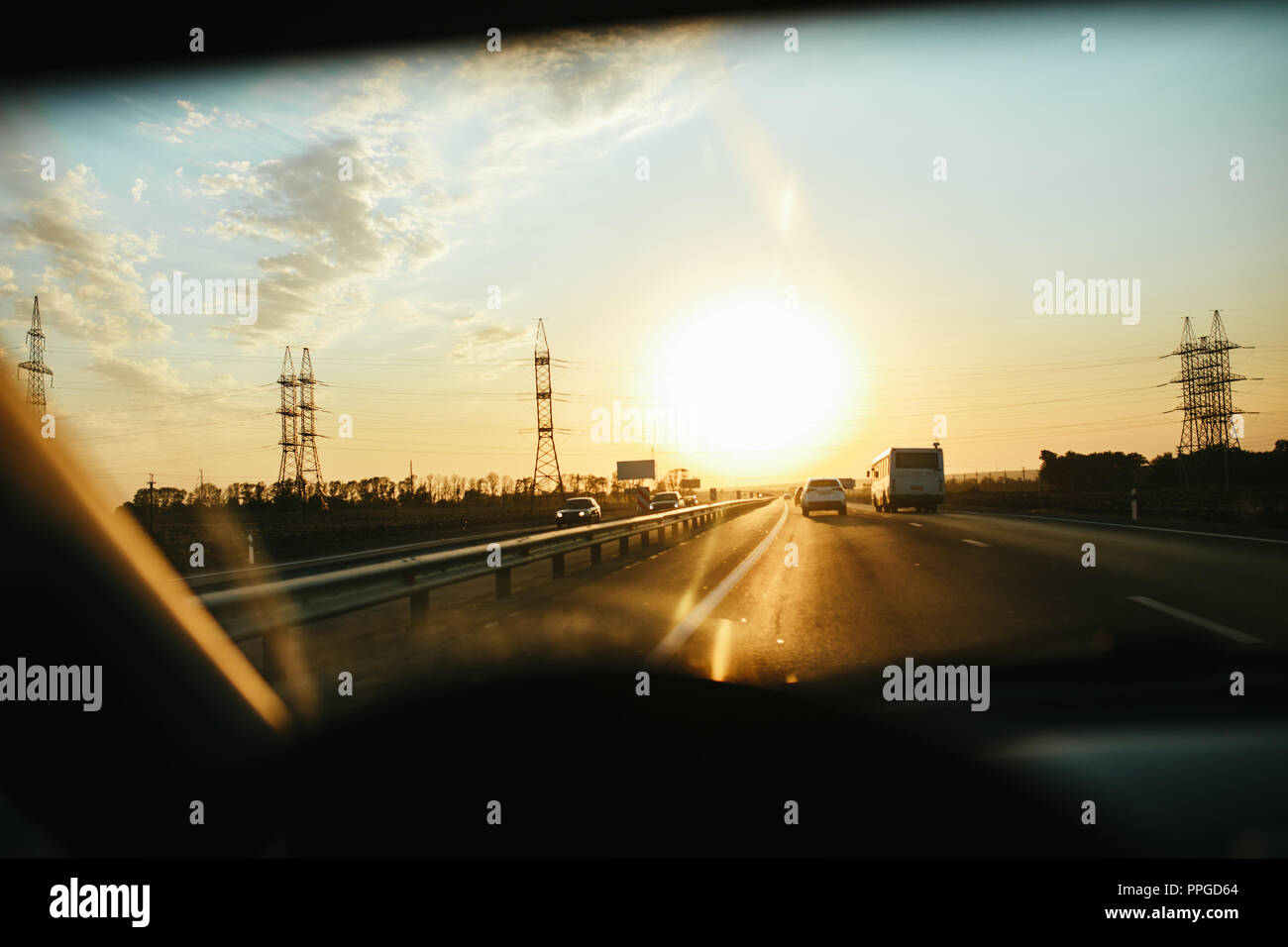 Selective focus asphalt road thru wind glass, driving a car at sunset. Travel background Stock Photo