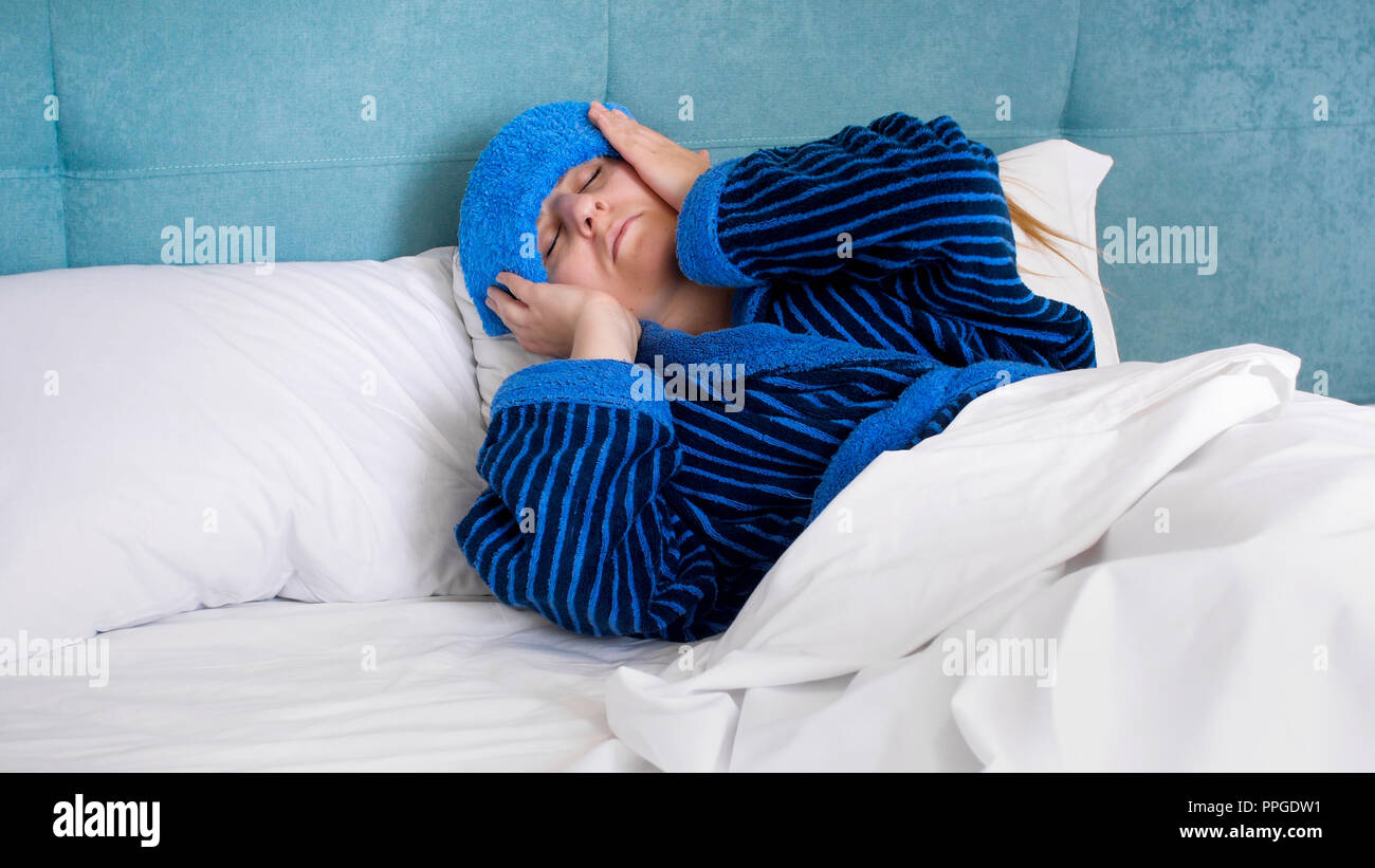 Portrait of sick woman with migraine lying in bed with wet towel on head  Stock Photo - Alamy