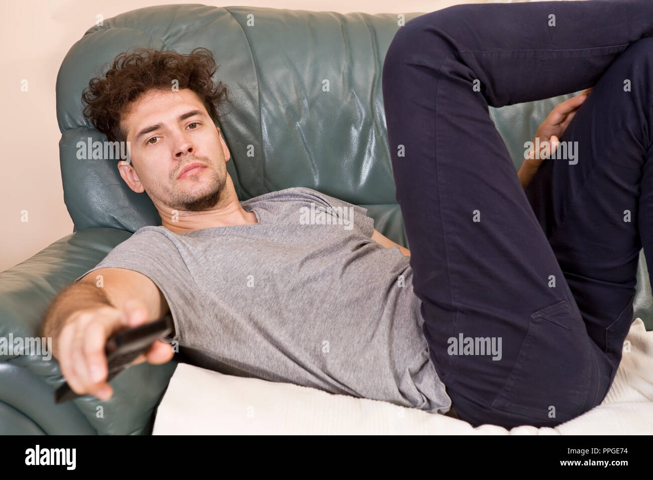 A young man watches television and changes channels while relaxing Stock Photo