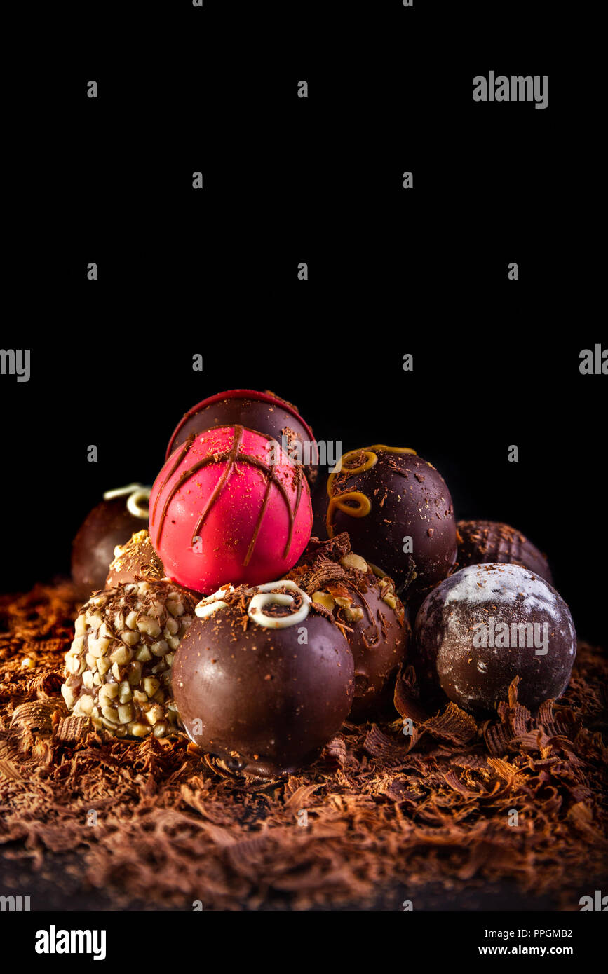 Set of assorted chocolate truffles illuminated with creative lighting, selective focus, black background and accommodation for copy space. Stock Photo