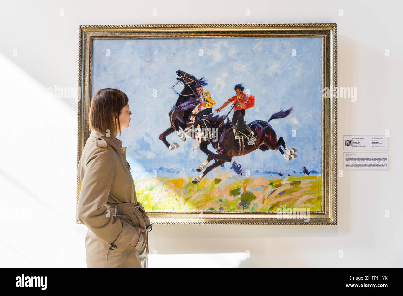 London, UK. 25th September 2018. A visitor views the oil on canvas, Kokpar, 1960 showing a traditional nomadic game by Kanafiya Telzhanov. The Focus Kazakhstan: Post-Nomadic Mind exhibition features emerging and established artists and examines Kazakh contemporary art as a form of multi-channel discourse, drawing parallel dialogues between contemporary artists, their Soviet predecessors, and the newly termed subject matter of post-nomadism. The exhibition runs until 16th October 2018. Credit: Vickie Flores/Alamy Live News Stock Photo