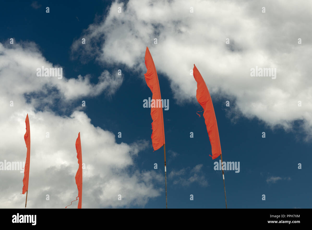 Vivid orange flags against blue sky on sunny day.Complementary colours concept. Stock Photo