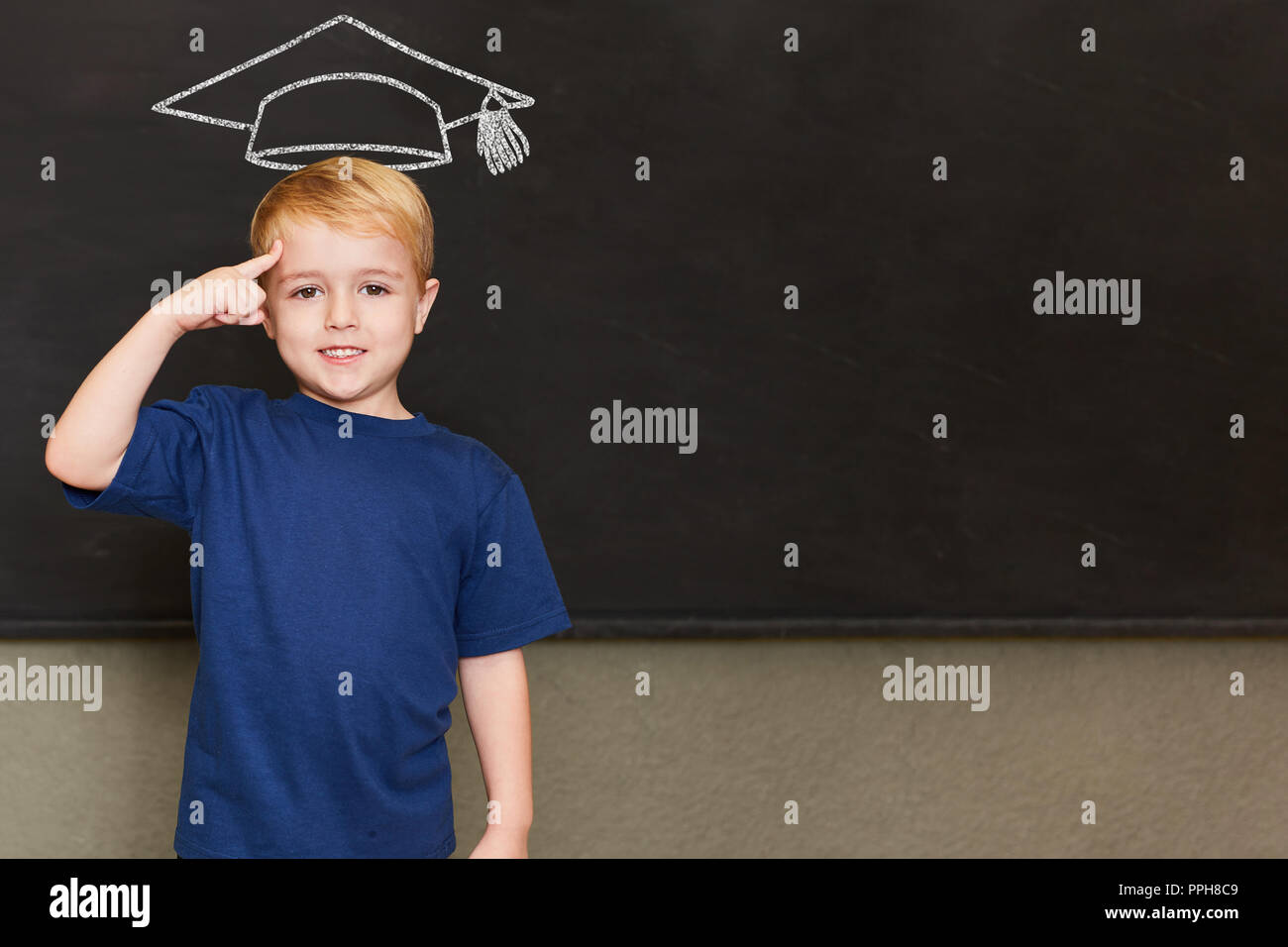 Pupils in school in front of blackboard with mortarboard as a symbol of knowledge and education Stock Photo