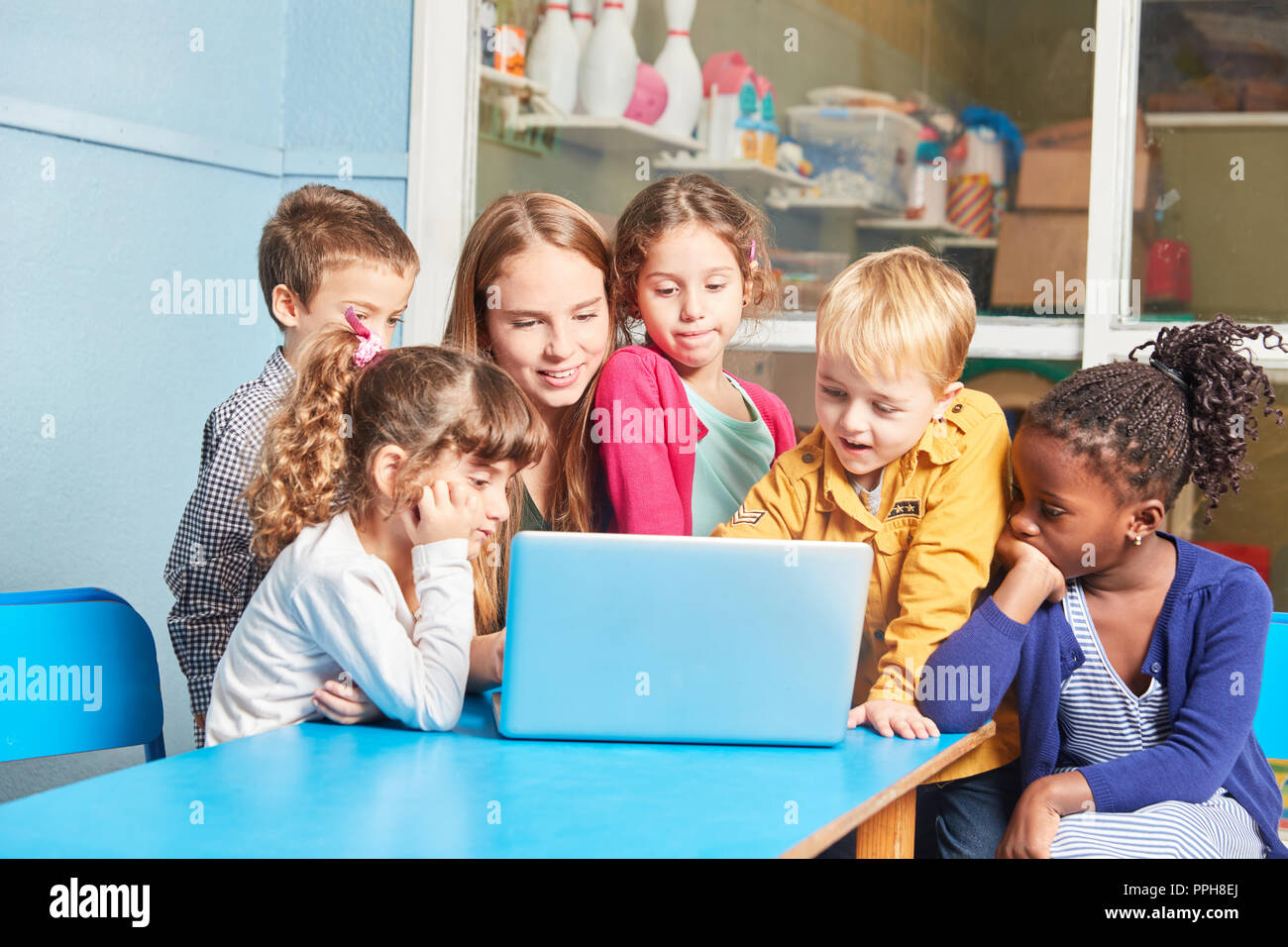 Teacher and group of children learning together at laptop computer in elementary school Stock Photo