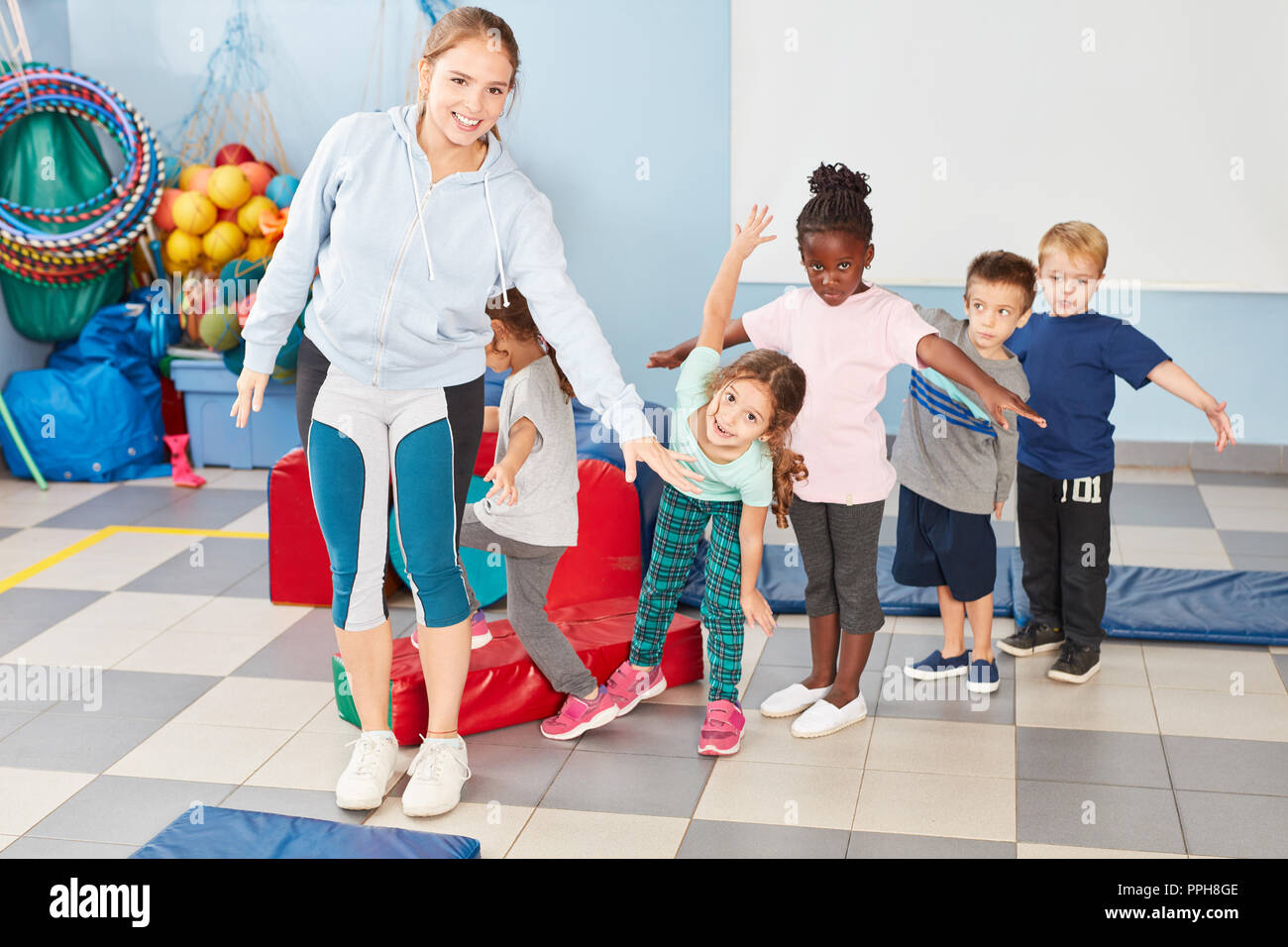Group of children and sports teacher together while doing gymnastics in gym class Stock Photo