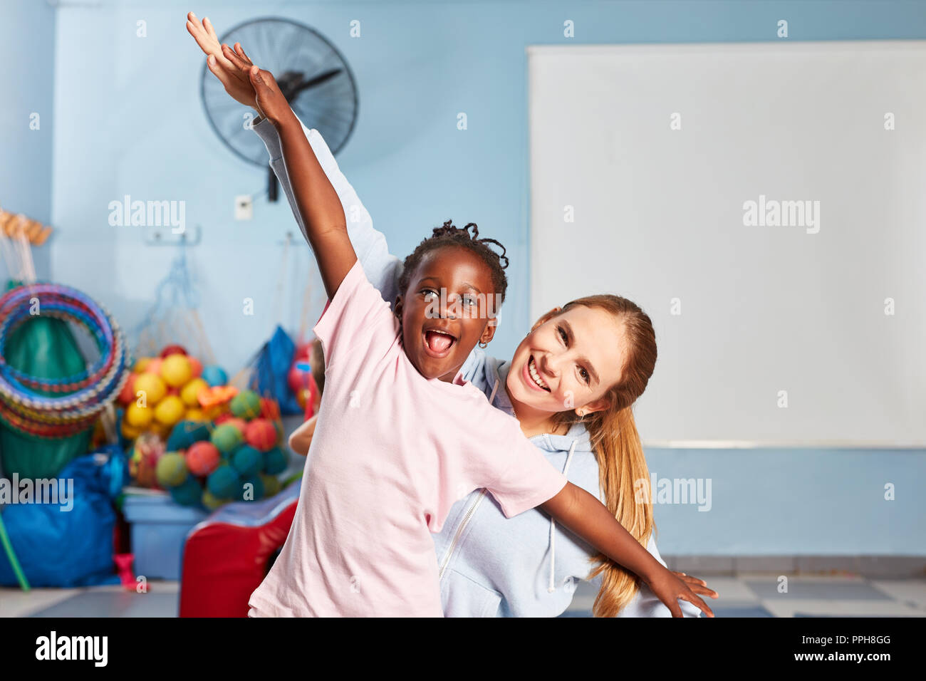Girl and sports teacher make gymnastics and fun in pre-school physical education Stock Photo