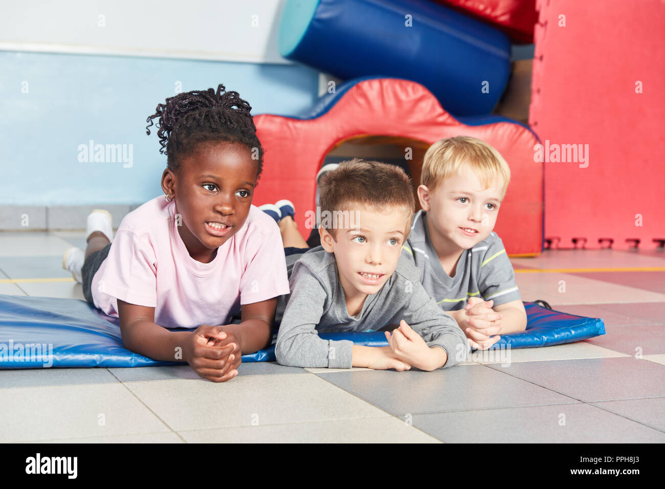 Multicultural children as friends in the gym in kindergarten or preschool Stock Photo