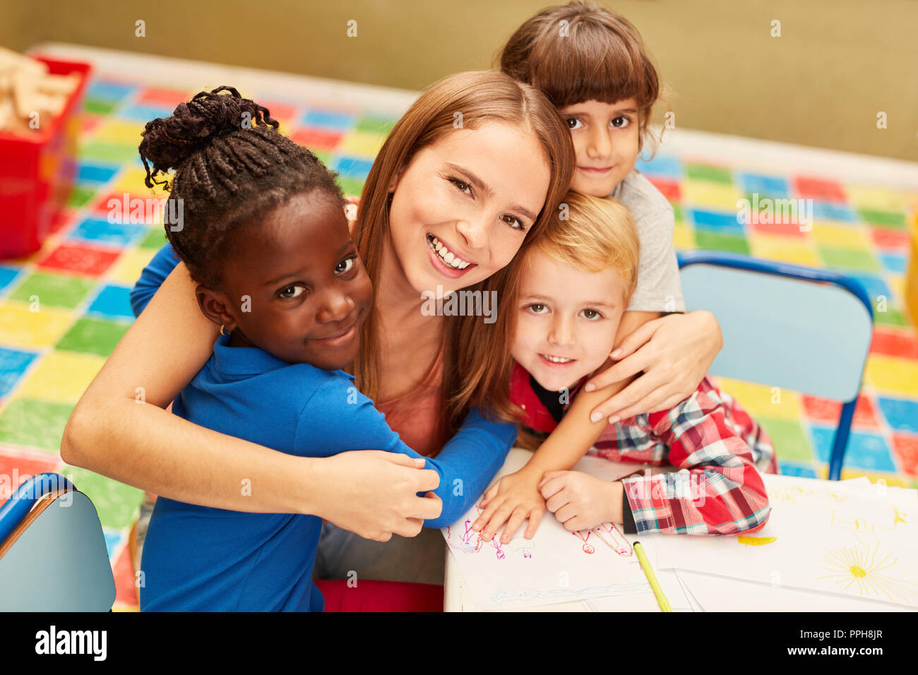 Happy woman as a teacher or childminder together with children in the day care center Stock Photo