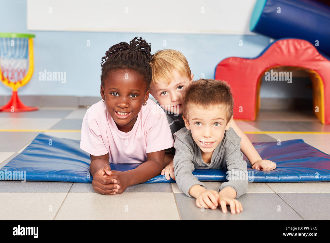Three multicultural children as best friends in the international kindergarten or daycare Stock Photo
