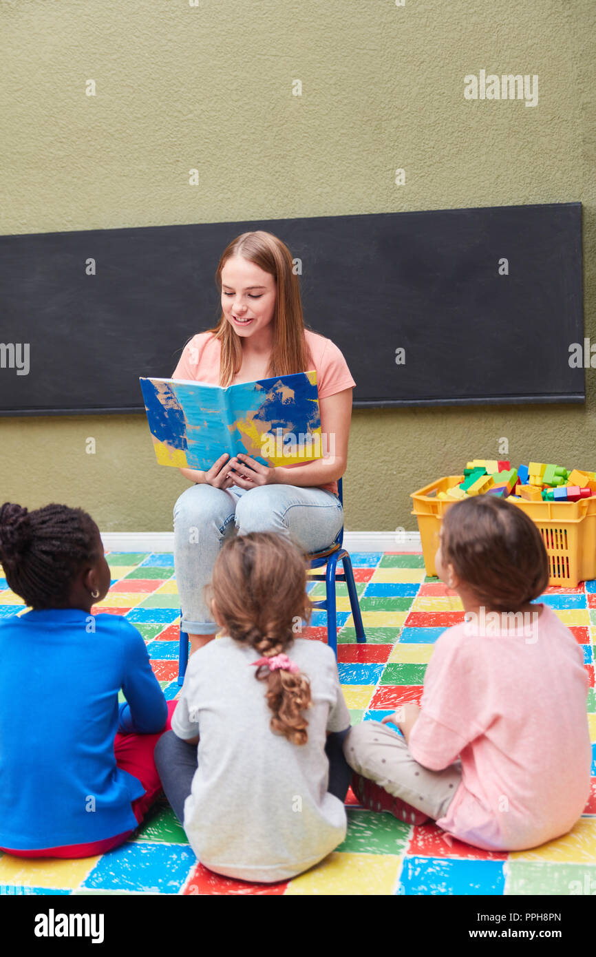 Children in kindergarten or preschool listen to when reading from a children's book Stock Photo