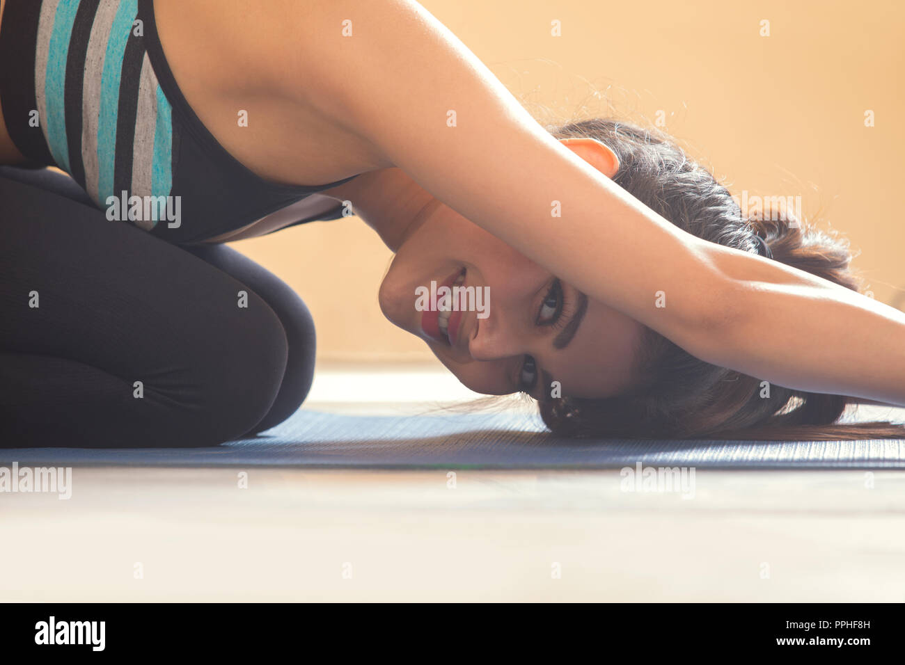 Close up of a smiling young woman in yoga posture. Stock Photo