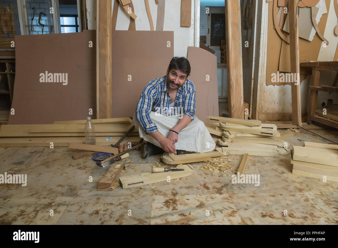 Carpenter making markings on wood sitting in his workshop. Stock Photo