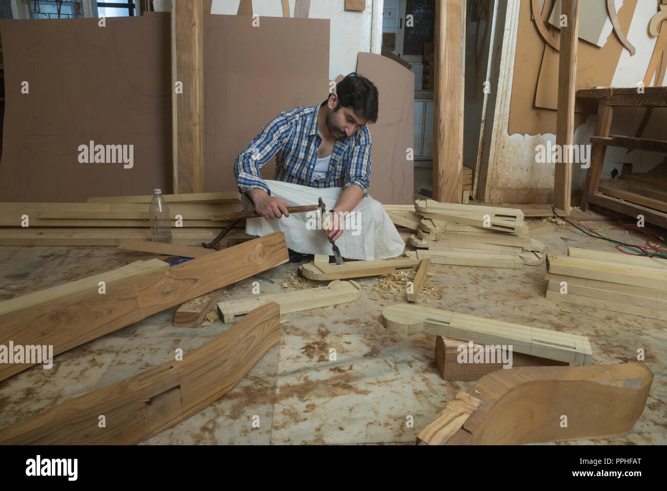 Carpenter working with a chisel and hammer sitting in his workshop. Stock Photo
