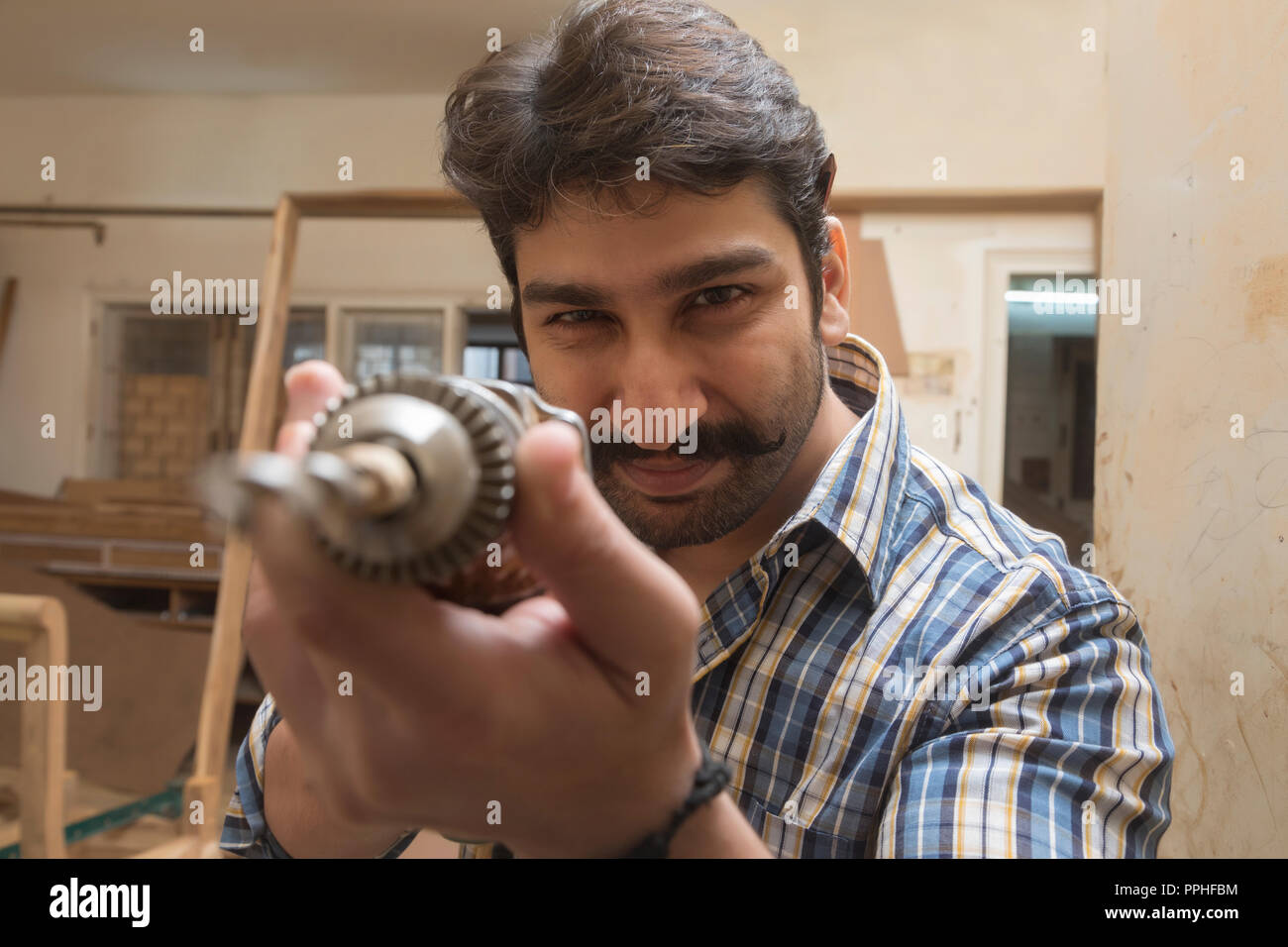 Close up of a carpenter in his workshop holding a drilling machine. Stock Photo