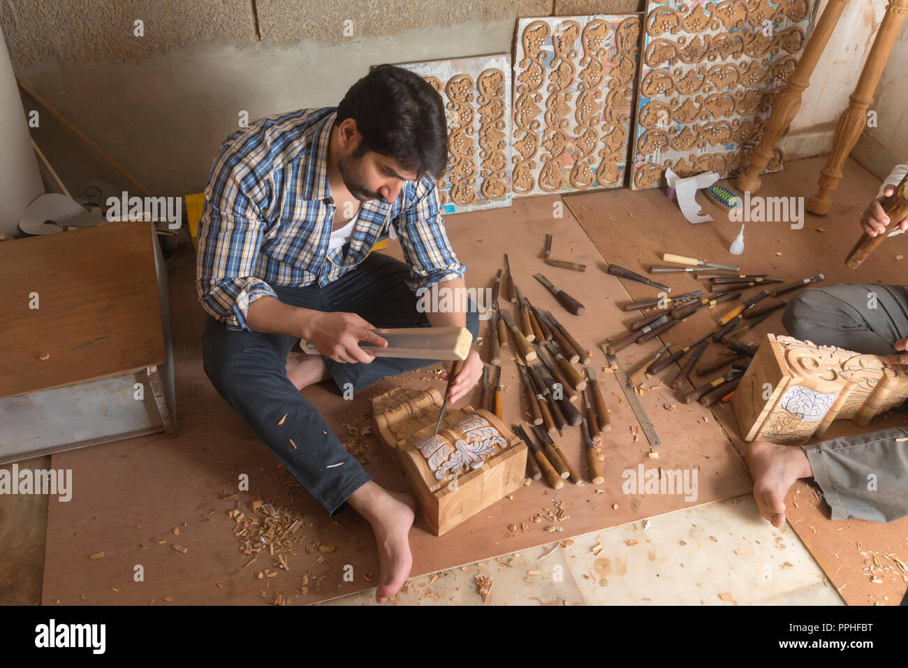 Carpenter using a chisel to make carvings and designs on wood in his workshop. Stock Photo