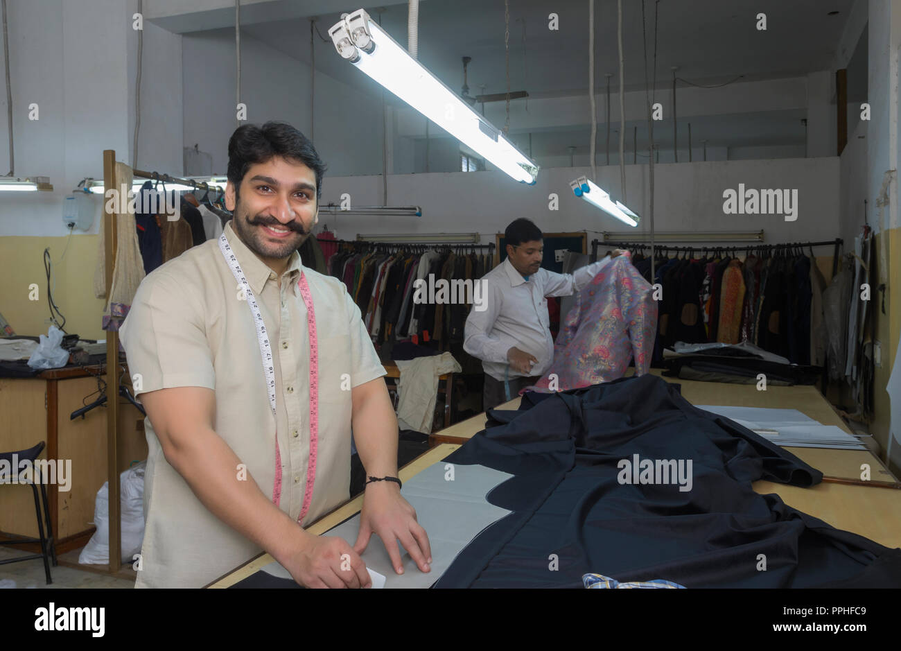 Happy tailor making markings on cloth in his workshop. Stock Photo