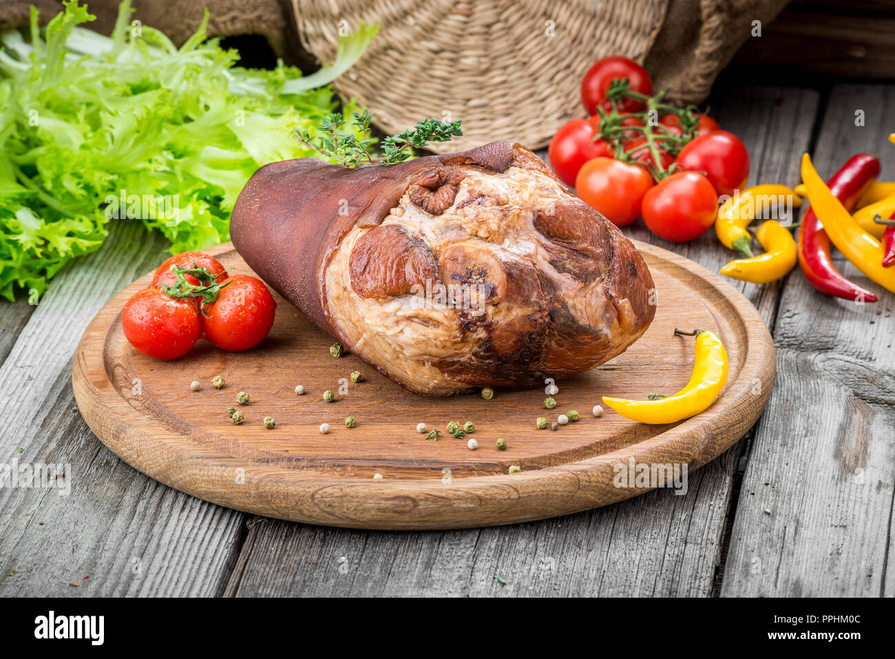 Smoked ham hock with herbs and spices on wooden plate. Stock Photo