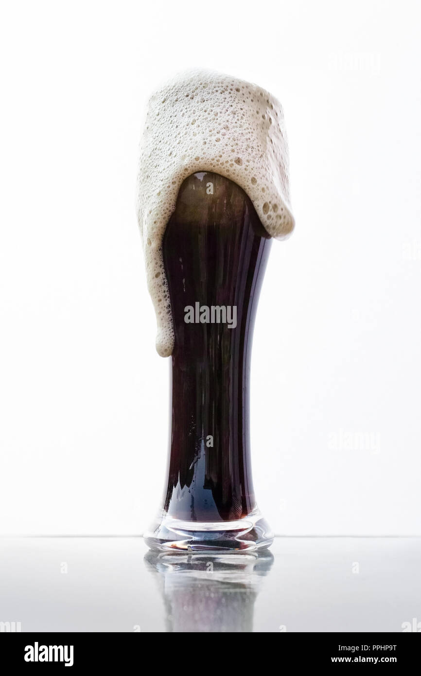 a pint of black beer, the foam overflows. Stock Photo