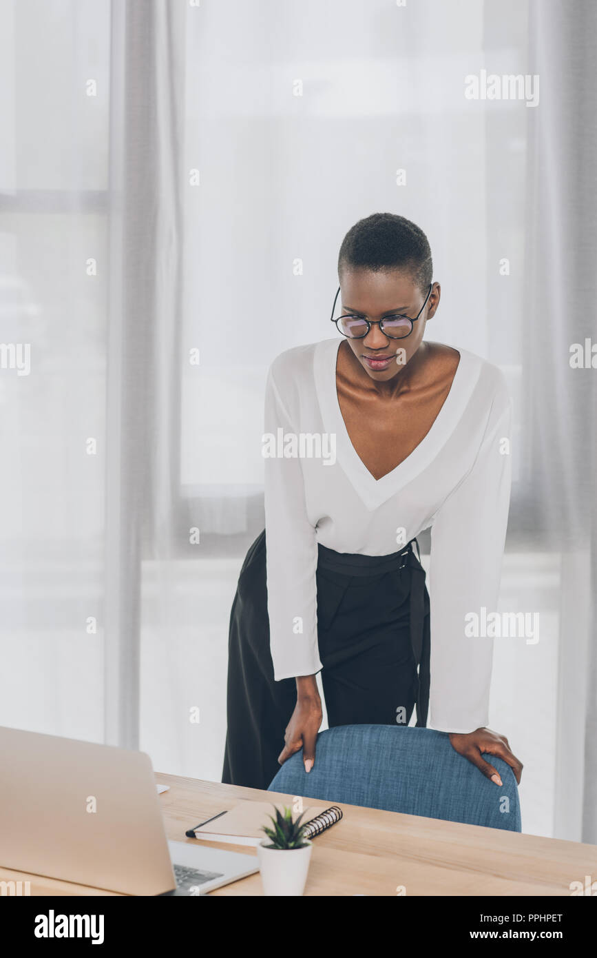stylish attractive african american businesswoman leaning on armchair ...
