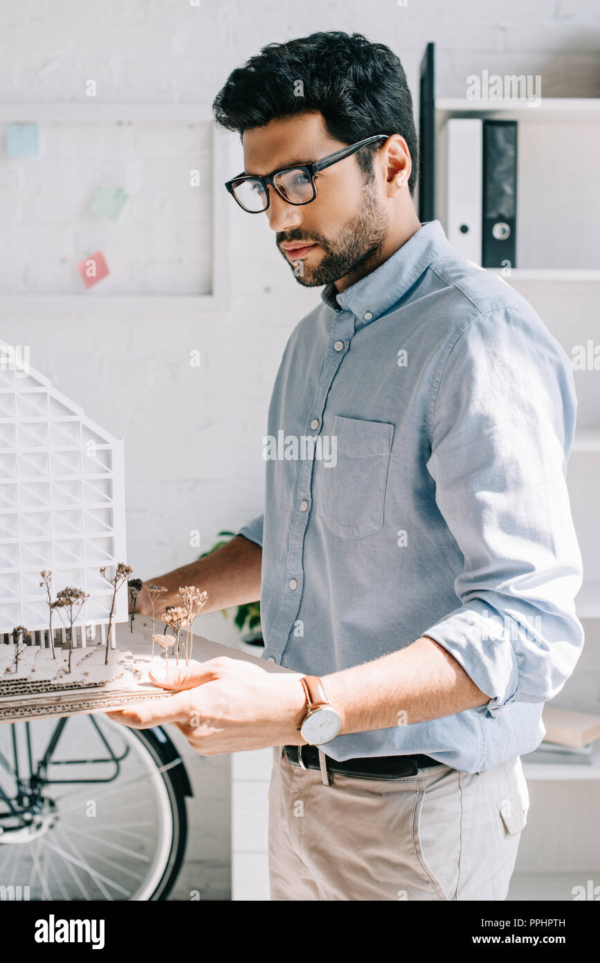 side view of handsome architect holding architecture model in office Stock Photo
