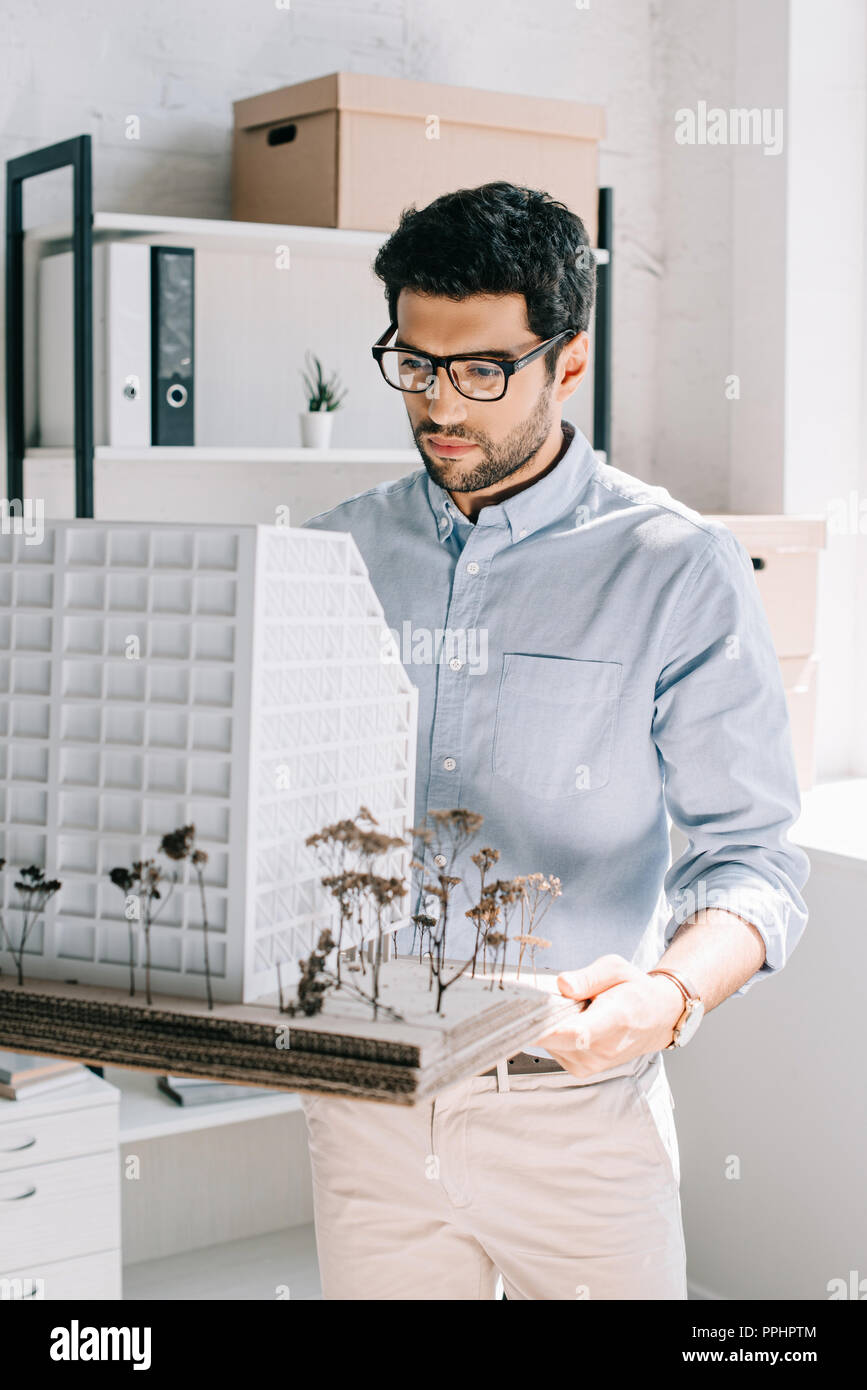 handsome architect holding and looking at architecture model in office Stock Photo