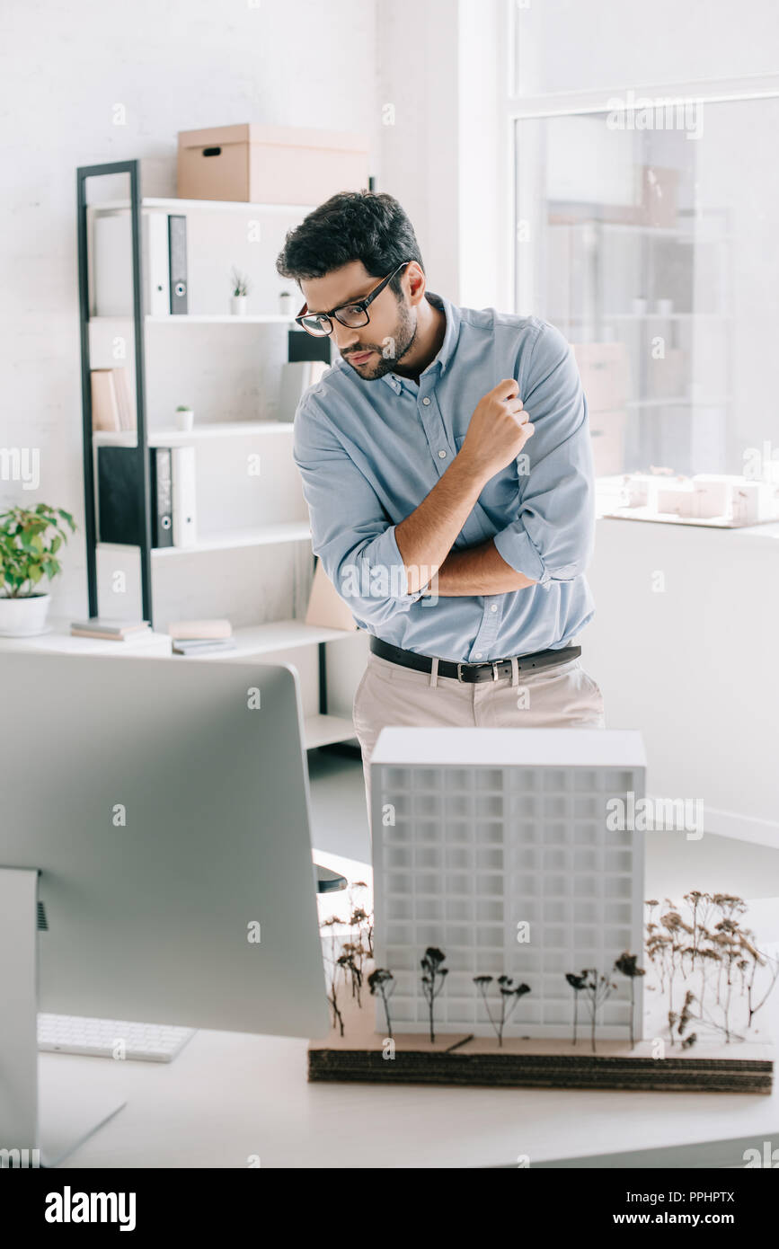 handsome architect looking at computer near architecture model on table in office Stock Photo