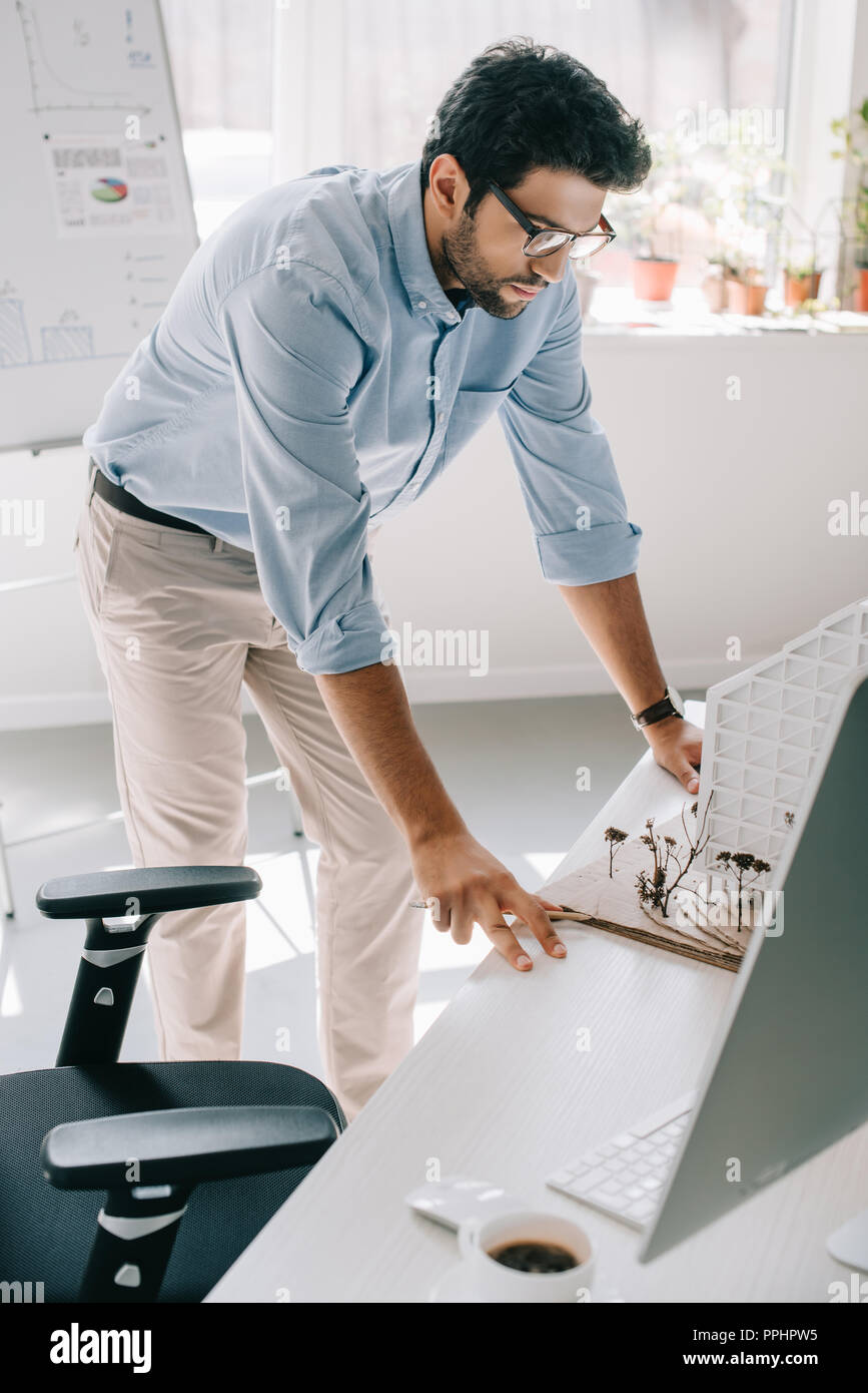 handsome architect leaning on table and looking at architecture model in office Stock Photo