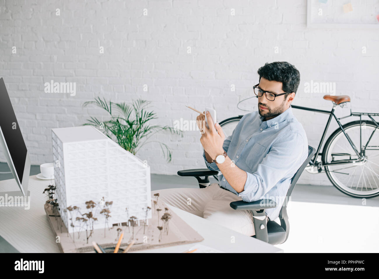handsome architect using smartphone near architecture model in office Stock Photo