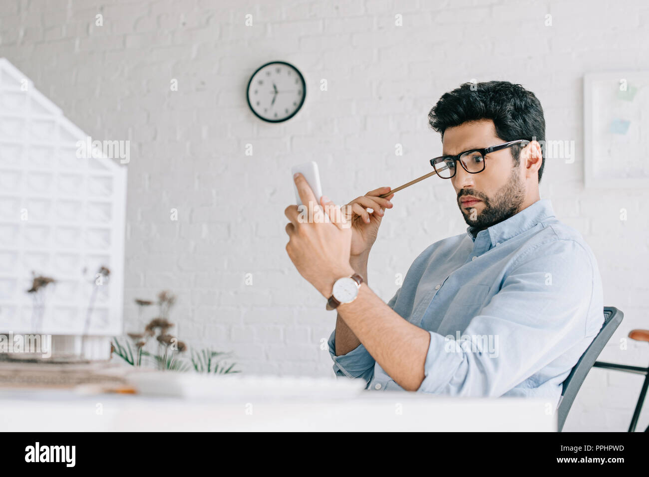 shocked architect using smartphone near architecture model in office Stock Photo