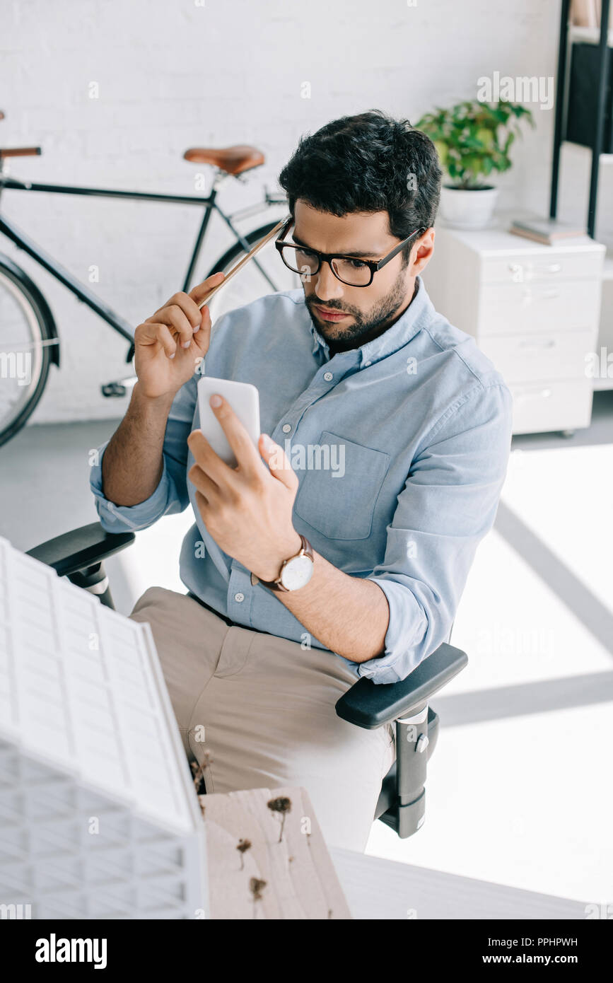 serious architect using smartphone near architecture model in office Stock Photo