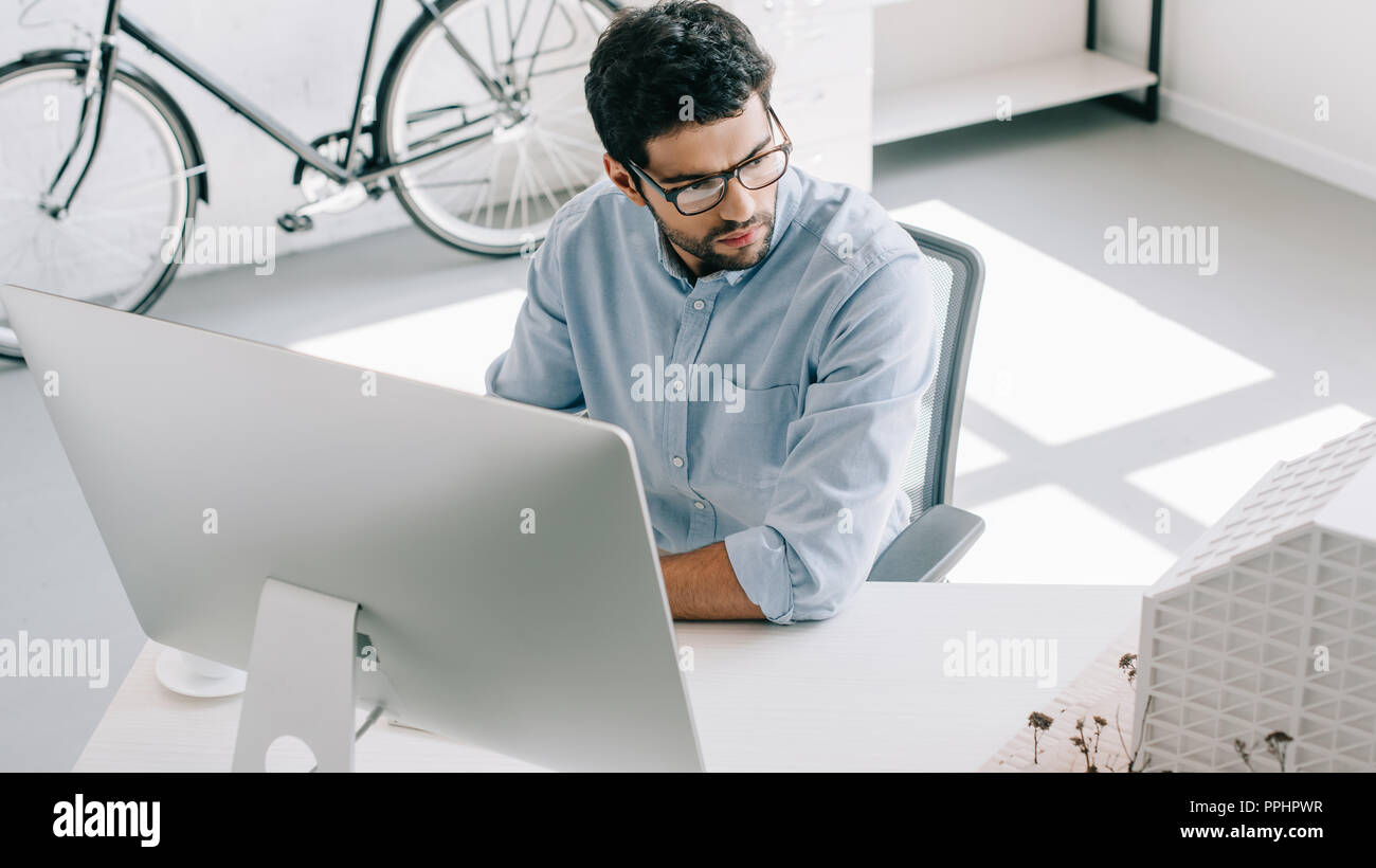 handsome architect using computer and looking at architecture model in office Stock Photo