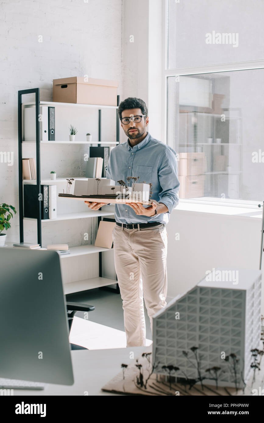 handsome architect holding architecture model in office and looking at camera Stock Photo