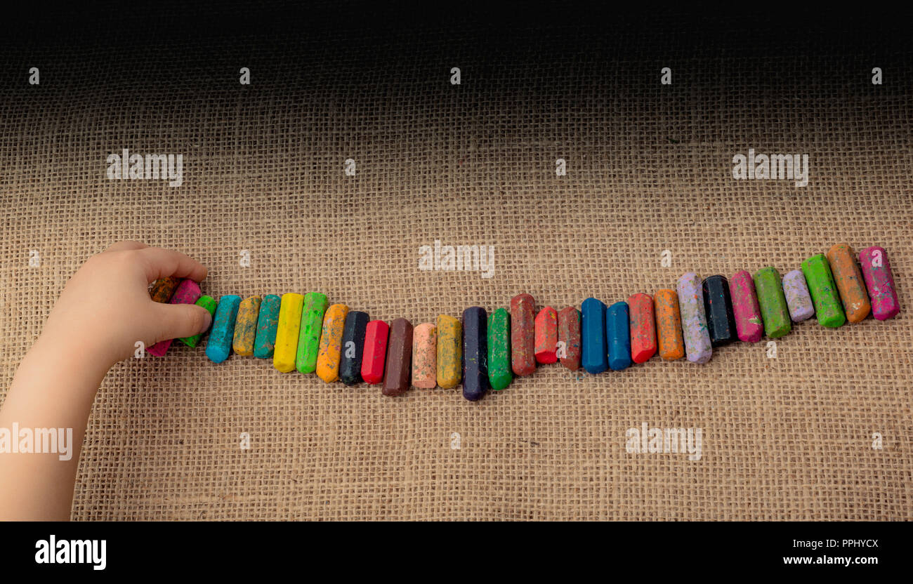 toddlers hand putting crayons in line on canvas stock photo