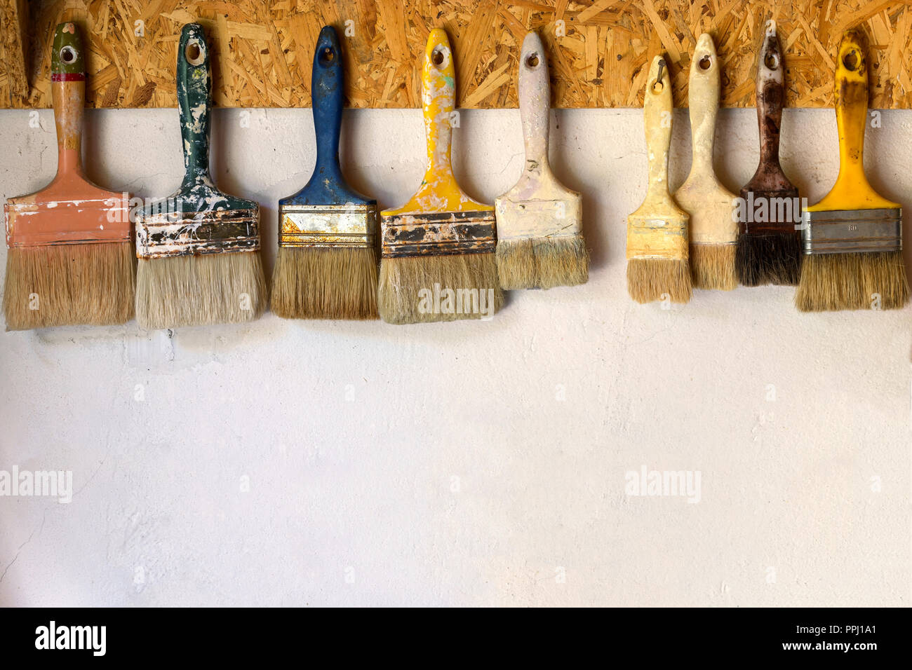 Old paint brushes hanging on a wall Stock Photo