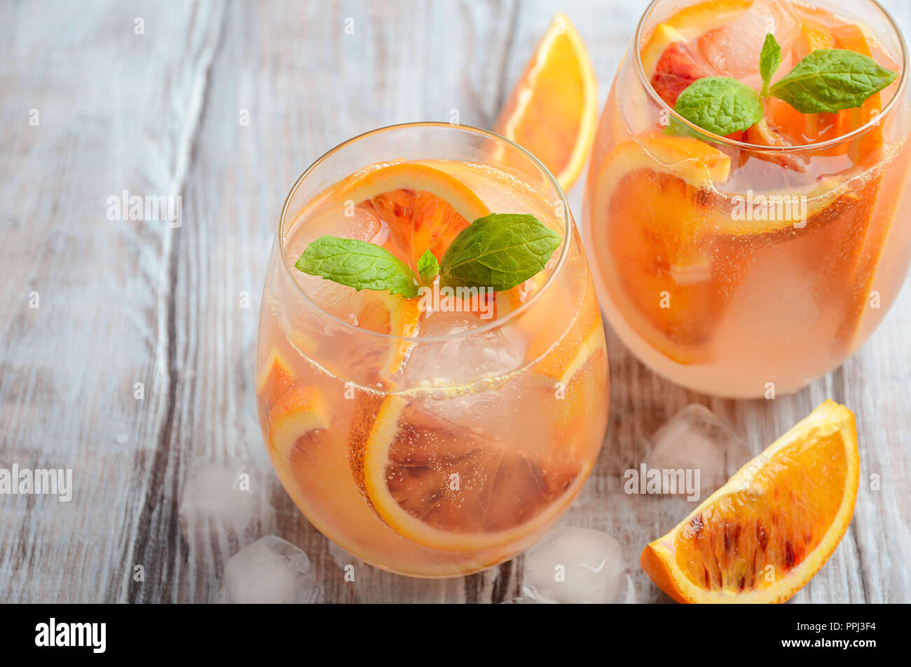 Cold refreshing drink with blood orange slices in a glass on a wooden background. Stock Photo