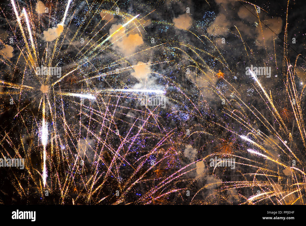 Salute in the night sky. Bright texture of festive fireworks. Abstract holiday background with various colors fireworks light. New Year's, Christmas l Stock Photo