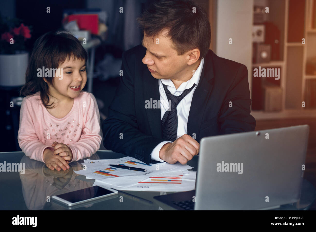 Daughter helping father working at home Stock Photo